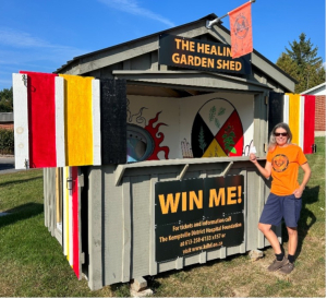 Kelly Johnson holds her winning ticket in front of The Healing Garden Shed which was on display on County Road 44, Kemptville. Constructed by Timely Touchups, Oxford Station, the interior was painted by Aurora Jade, an Ottawa-based Indigenous artist. 