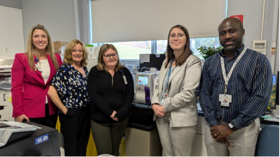 The blood analyser machine sits on the counter between, (l-r), Katie Hogue, VP of Nursing/Clinical Services and Chief Nursing Executive, Joanne Mavis, ED, KDH Foundation, Sabrina, lab technician, Cassandra Mayville-Fortin, RN, KDH Manager of Emergency, Care Quality, & Education and Edwin Nkengla, EORLA Site Operations Manager